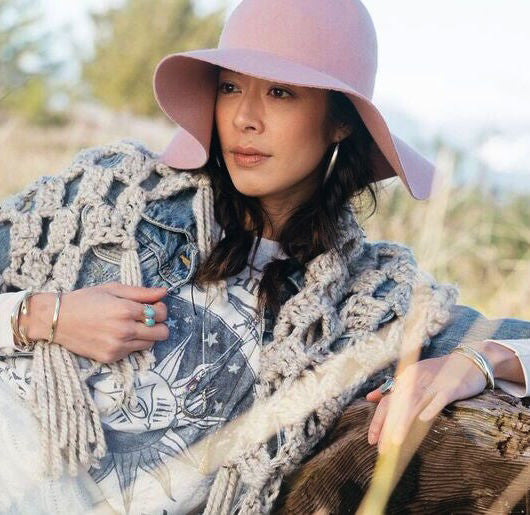 woman wearing multiple bracelets and jean jacket and pink hat 